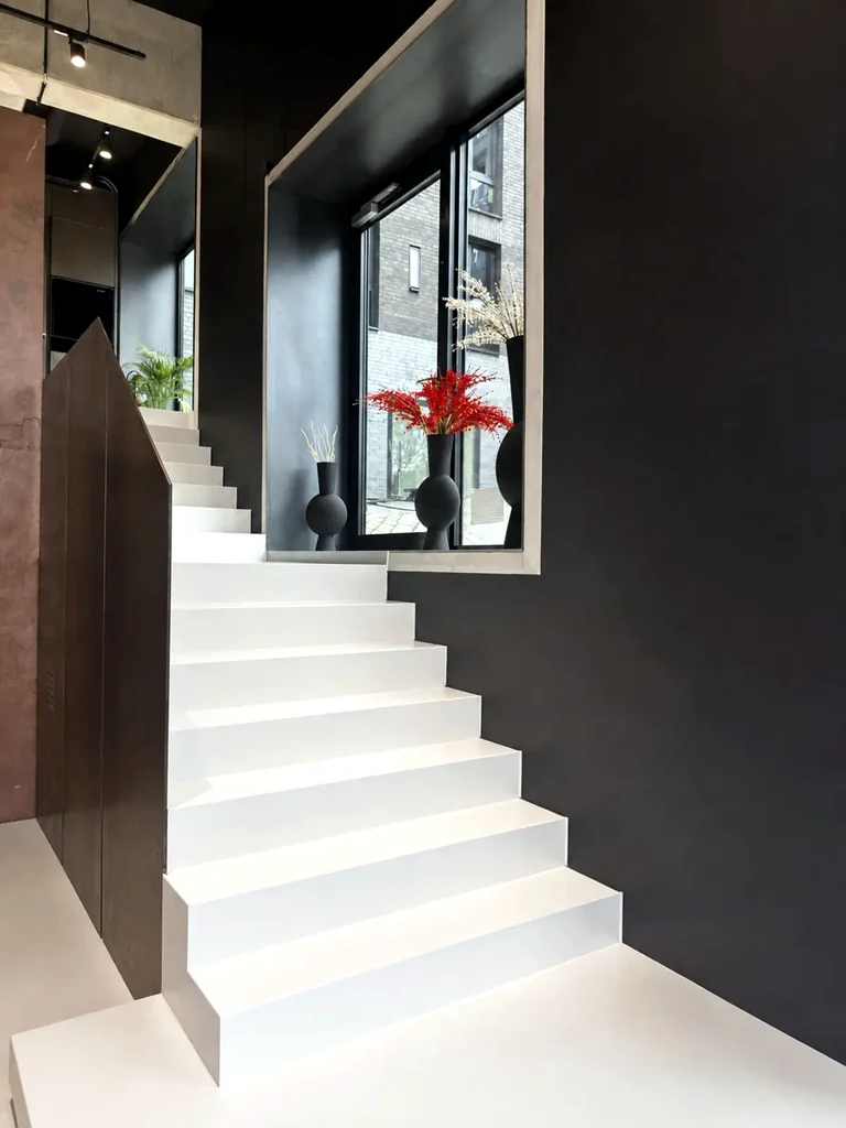 Weiße Designtreppe vor dunkler Wand in einem hochwertigen Showroom