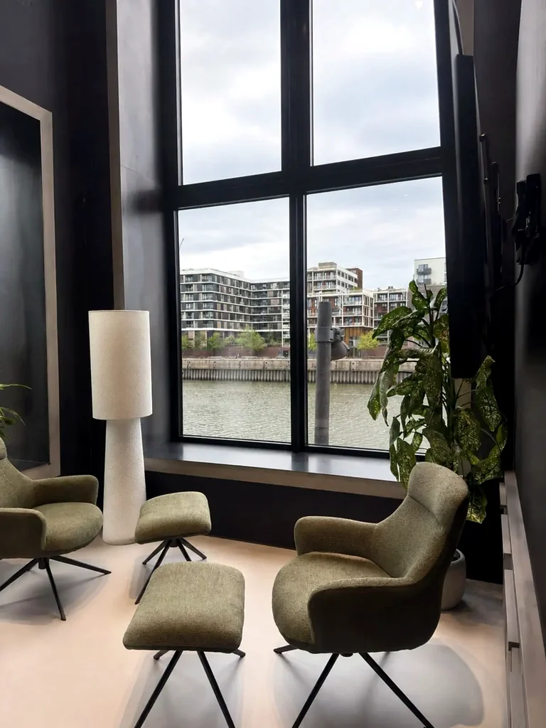 Loungebereich mit gepolsterten Sesseln und Blick auf das Wasser